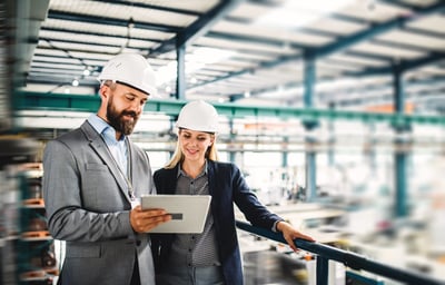 Un responsable production industrielle avec une membre de son équipe dans une usine de travail.